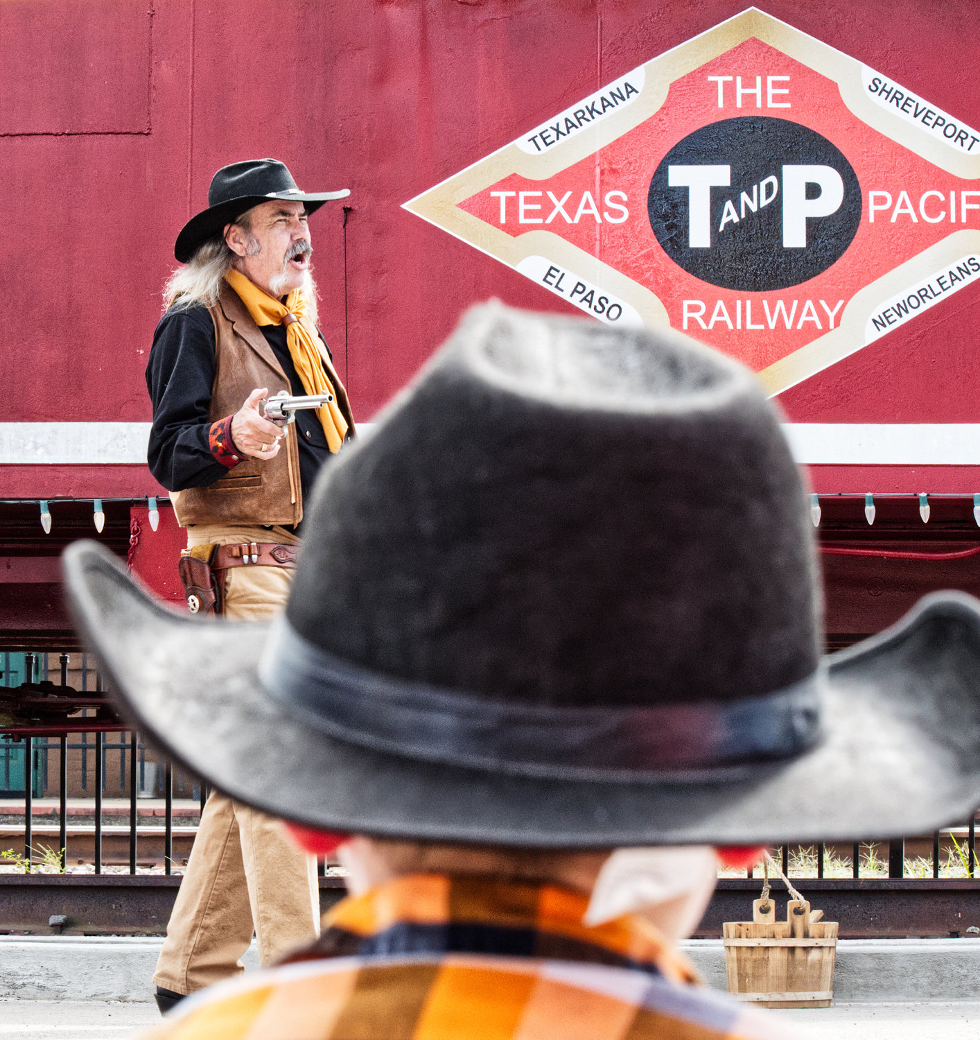 A youngster looks on as the sheriff investigates a train robbery (reenactment).